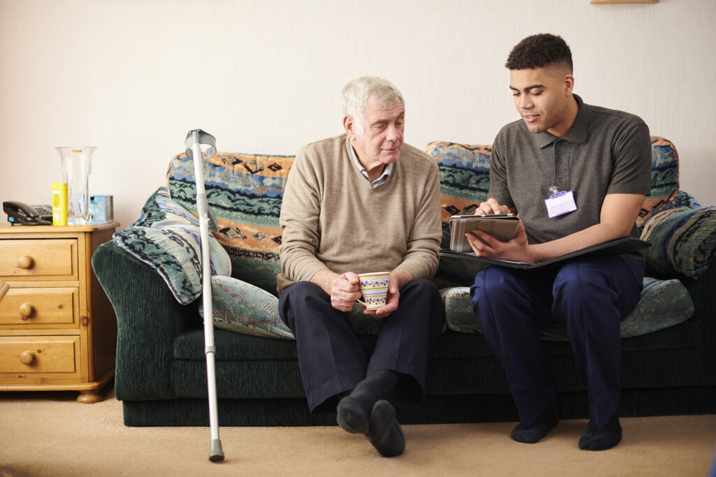 personal care support worker sitting with elderly man